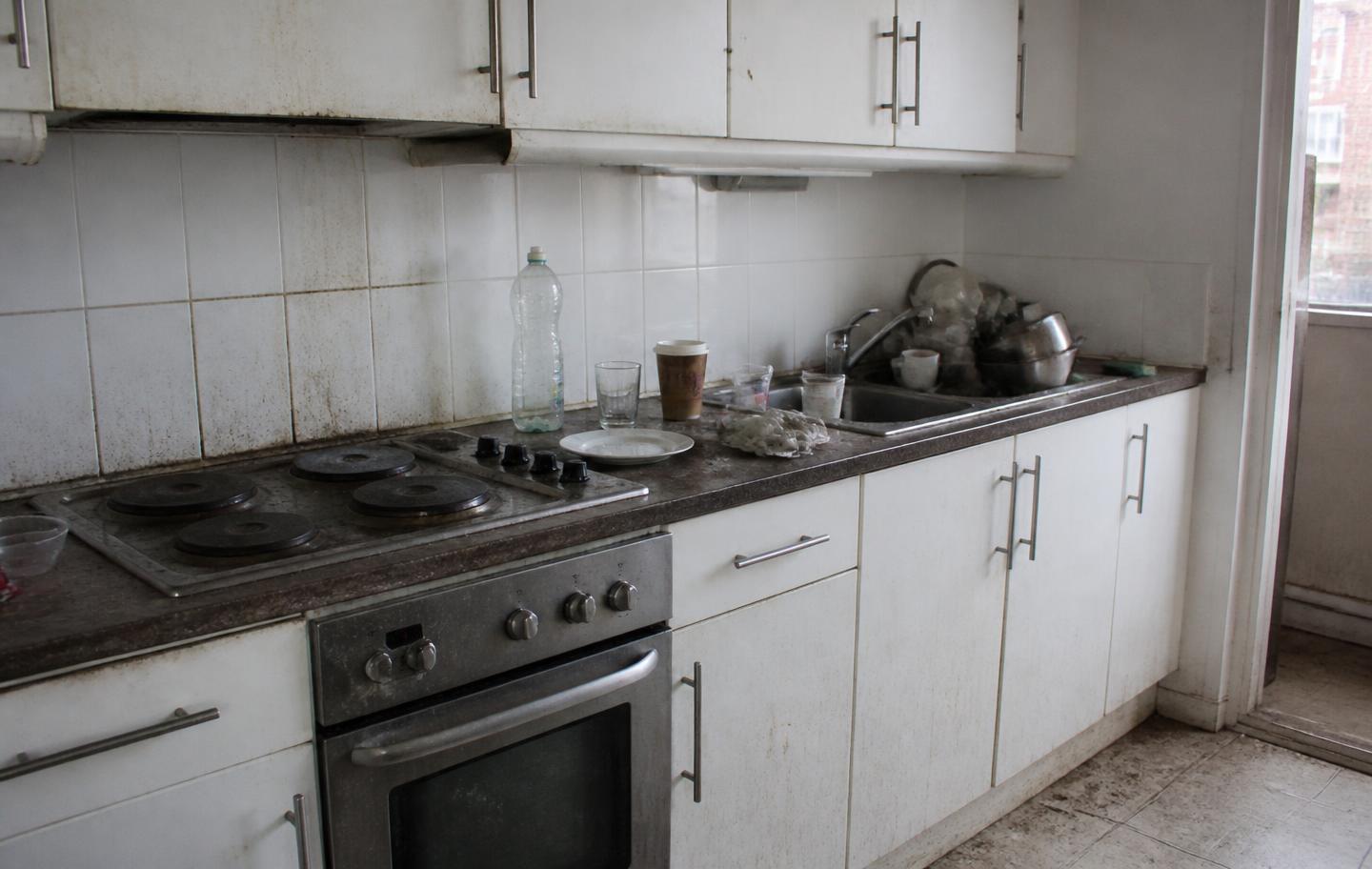 Kitchen before cleaning with cluttered counters and grease
